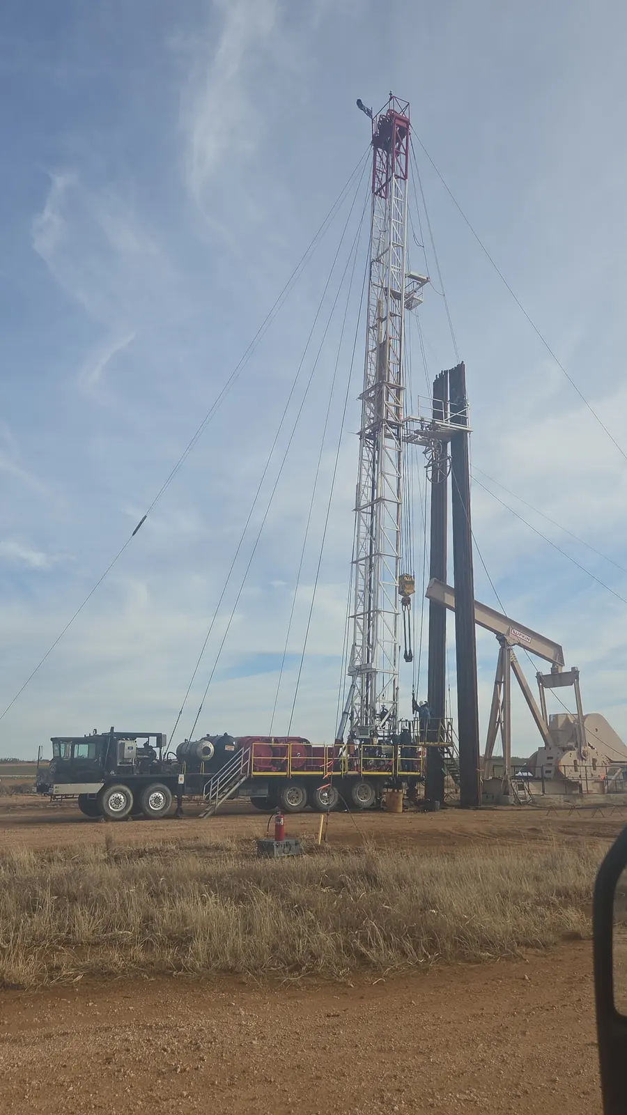 A well-service rig parked beside a pumpjack